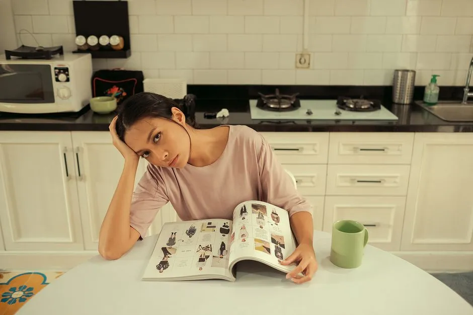 Woman at a kitchen table answering timed mental maths on a laptop with a notebook pushed aside