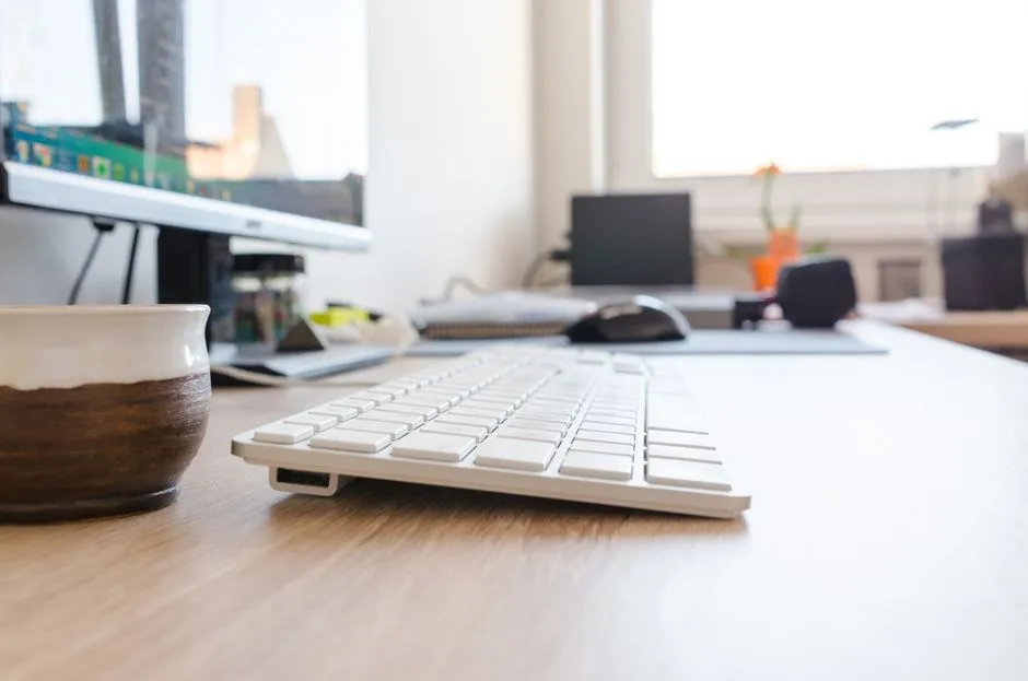 Simple desk setup with lamp, keyboard and a stopwatch sitting next to an open browser tab