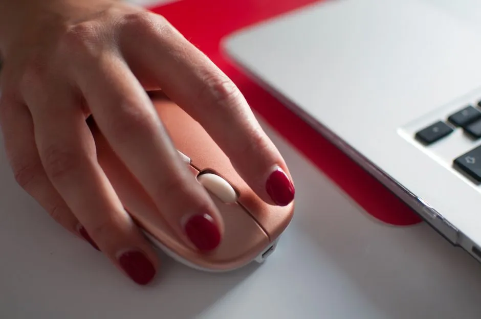 Close-up of a hand on a mouse, finger poised over the button, browser drill screen glowing at the edge of frame